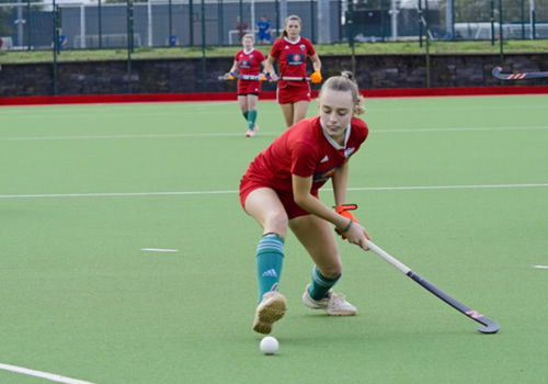 female hockey player stretching for the ball with one foot in the air